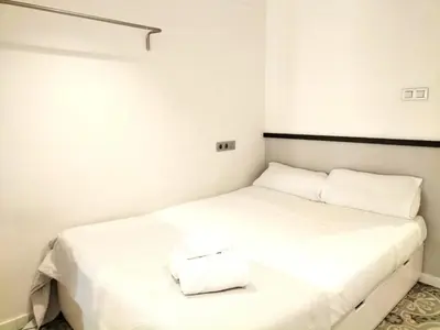 two beds in a room with white walls at Liceu Apartments by gaiarooms in Barcelona