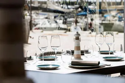 a table with wine glasses and a lighthouse on it at Hotel Marina Badalona in Badalona