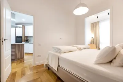 a white bedroom with a bed and a kitchen at Majestic 4BR/4BATH apartment in Sagrada Familia area in Barcelona