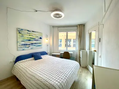 a bedroom with a bed and a painting on the wall at Piscina en Centro de Terrassa in Terrassa