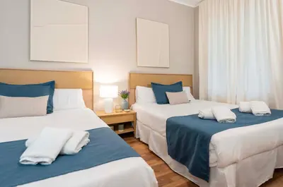 a bedroom with two beds with blue and white sheets at Sagrada familia Secret Apartment in Barcelona