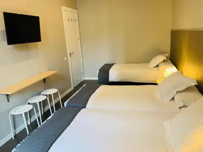 two beds in a room with a tv and stools at Super Balmes Guest House in Barcelona