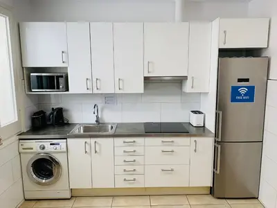 a kitchen with white cabinets and a stainless steel refrigerator at Super Balmes Guest House in Barcelona