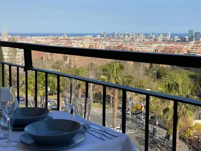a table with plates and wine glasses on a balcony at Amazing sea and Sagrada Familia views homey apartment in Barcelona