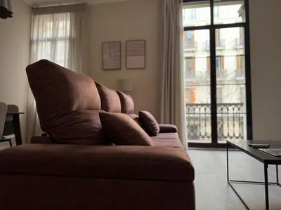 a brown couch in a living room with a window at Anais Apartments by gaiarooms in Barcelona