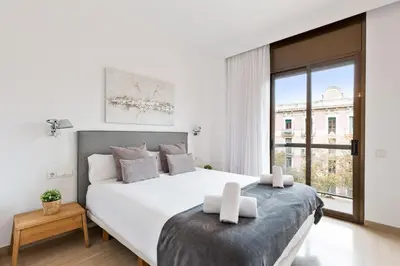 a white bedroom with a large bed and a window at Stay U-nique Apartments Sant Antoni II in Barcelona
