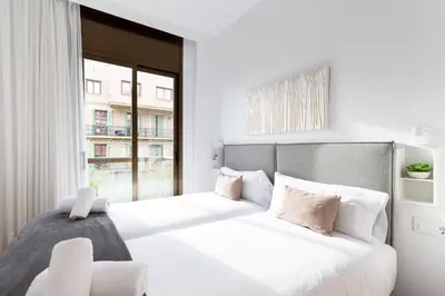 a white bedroom with two beds and a window at Stay U-nique Apartments Sant Antoni II in Barcelona