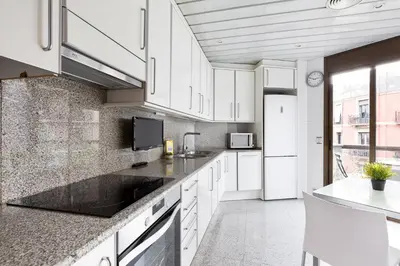a kitchen with white cabinets and a large window at Stay U-nique Apartments Sant Antoni II in Barcelona