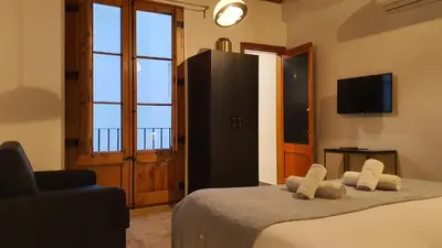 a bedroom with a bed with a television and a chair at Barrio Gotico Apartments Escudellers in Barcelona