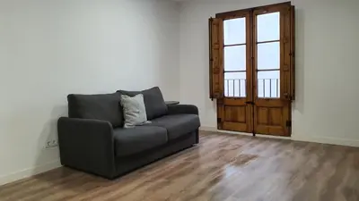 a living room with a couch and a wooden door at Barrio Gotico Apartments Escudellers in Barcelona
