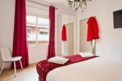 a bedroom with red curtains and a bed and a chair at Apartment Eduardo in Barcelona