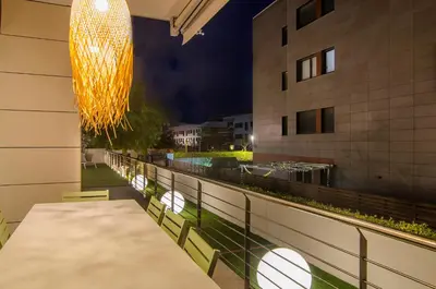 a dining table on the balcony of a building at night at Sitges Spaces Garden Paradise 3 bedroom, 3 bathroom, huge PRIVATE garden-terrace, pool- sleeps up to 8 in Sitges