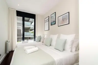 a white bedroom with a large white bed and a window at Sitges Spaces Garden Paradise 3 bedroom, 3 bathroom, huge PRIVATE garden-terrace, pool- sleeps up to 8 in Sitges