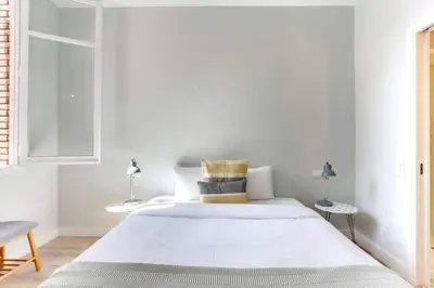 a white bedroom with a large bed and two tables at Bright 2bdr In Trendy Gracia in Barcelona
