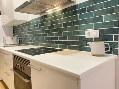 a kitchen with green tiles on the wall at Lovely New apartment 20 minutes from Barcelona center. in Barcelona