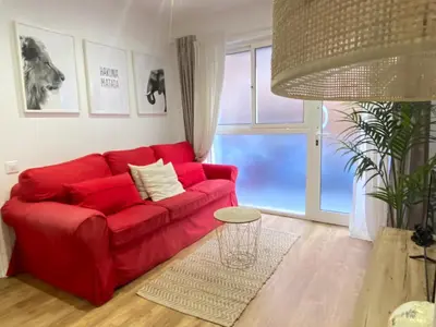 a red couch in a living room with a large window at Lovely New apartment 20 minutes from Barcelona center. in Barcelona