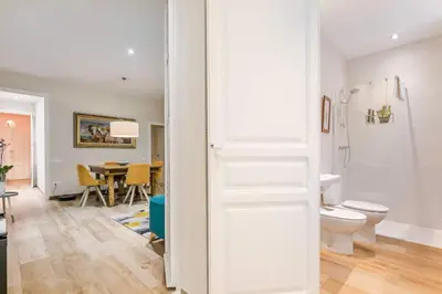 a white bathroom with a toilet and a dining room at Lovely Designed House Connected To Center in Cornellà de Llobregat