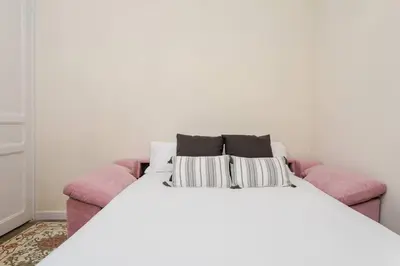 a white bed with two pillows on a pink couch at Lovely Designed House Connected To Center in Cornellà de Llobregat