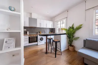 a kitchen with white cabinets and a black counter top at Caliu Apartments Barcelona - Fira in Hospitalet de Llobregat