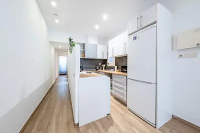a kitchen with white cabinets and a white refrigerator at Caliu Apartments Barcelona - Fira in Hospitalet de Llobregat