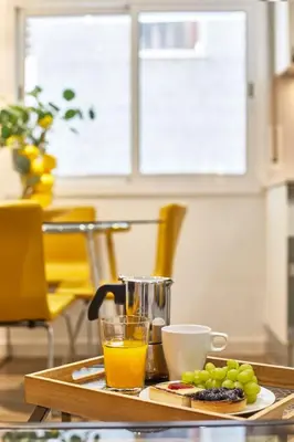 a table with a glass of orange juice and some grapes at BBarcelona Sant Pau Flat in Barcelona