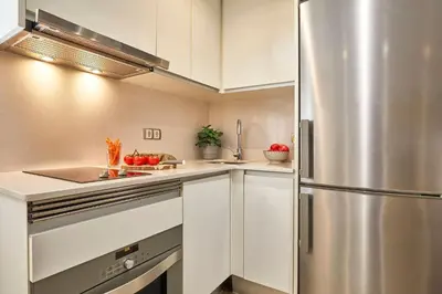 a kitchen with white cabinets and a stainless steel refrigerator at BBarcelona Sant Pau Flat in Barcelona