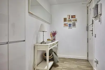 a white hallway with a table with a lamp on it at BBarcelona Sant Pau Flat in Barcelona