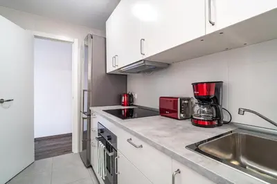a kitchen with white cabinets and a red appliance at LOVELY APARTMENT Barca 2 in Sant Adria de Besos