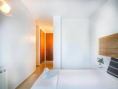 a bedroom with white walls and a white bed at Molins Apartment by Hello Homes Sitges in Sitges
