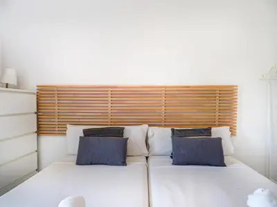 a large white bed with two blue pillows on it at Molins Apartment by Hello Homes Sitges in Sitges