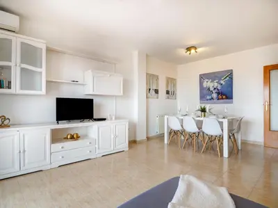 a living room with a television and a table with chairs at Molins Apartment by Hello Homes Sitges in Sitges