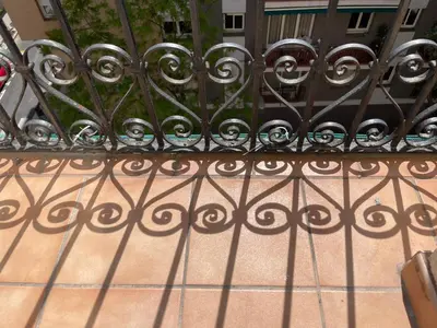a wrought iron fence with its shadows on a sidewalk at Apartamento Kemacu in Barcelona