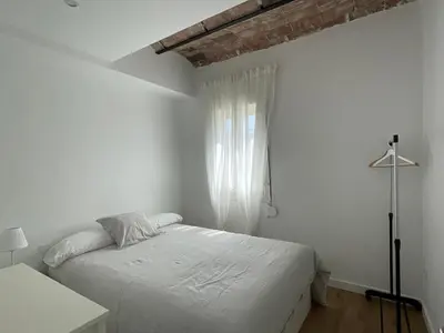 a white bedroom with a bed and a window at Apartamento Kemacu in Barcelona