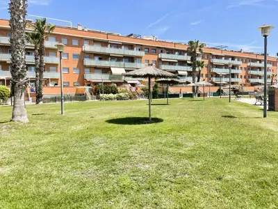 a park with an umbrella in front of a building at Onze - primera línea de mar con piscina in Cubelles