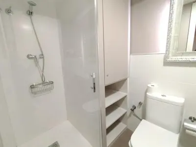 a white bathroom with a toilet and a shower at Montserrat Apartments by gaiarooms in Barcelona