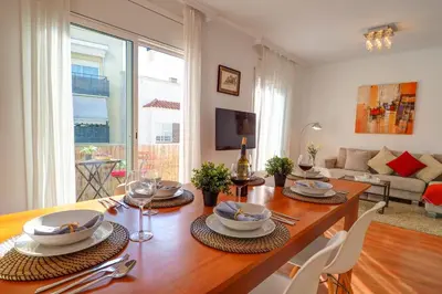 a dining room with a table and chairs and a living room at San Sebastian Apartment by Hello Homes Sitges in Sitges