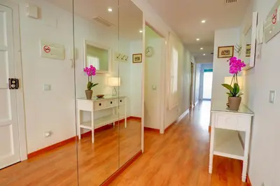 a hallway with a mirror and flowers in a room at San Sebastian Apartment by Hello Homes Sitges in Sitges