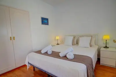 a bedroom with a large white bed with towels on it at San Sebastian Apartment by Hello Homes Sitges in Sitges