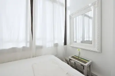a white bedroom with a bed and a mirror at The White Flats Sant Antoni in Barcelona