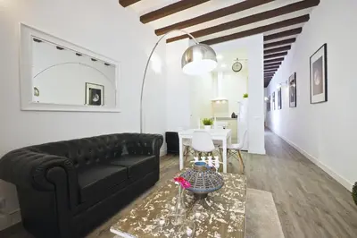 a living room with a black couch and a table at The White Flats Sant Antoni in Barcelona