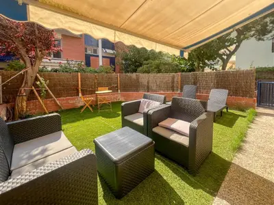 a patio with chairs and tables on the grass at Ocean Spirit House by Hello Homes Sitges in Sitges