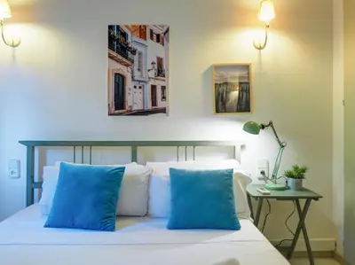 a bedroom with a bed with blue pillows and a table at Ocean Spirit House by Hello Homes Sitges in Sitges
