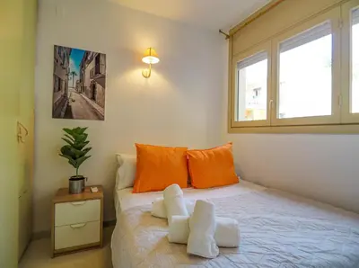 a bedroom with a bed with orange pillows and a window at Ocean Spirit House by Hello Homes Sitges in Sitges