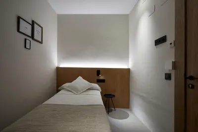 a small bedroom with a bed and a white wall at Ella Hostel Ramblas in Barcelona