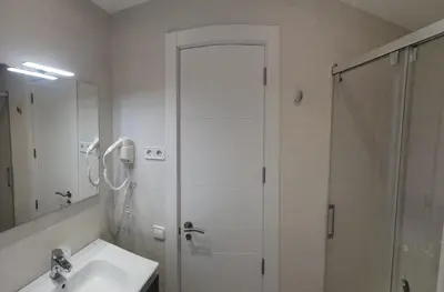 a white bathroom with a shower and a sink at Barcelona, Apartamento de 2 habitaciones. in Hospitalet de Llobregat