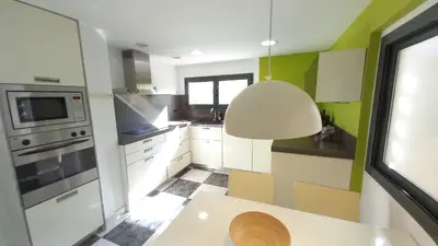 a kitchen with white cabinets and a large light fixture at Bright with pool near the beach and Barcelona by train in Masnou