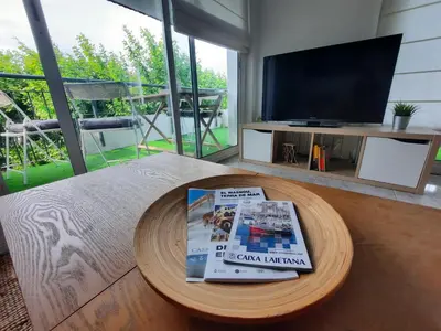 a magazine sitting on a coffee table in front of a tv at Bright with pool near the beach and Barcelona by train in Masnou