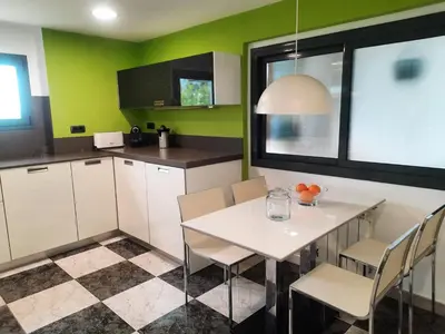 a kitchen with a table and chairs and green walls at Bright with pool near the beach and Barcelona by train in Masnou