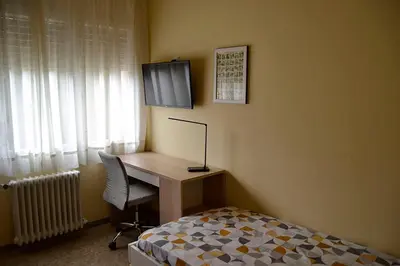a bedroom with a desk with a bed and a television at Cal Kim in Martorell