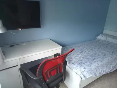 a bedroom with a desk and a red chair next to a bed at Cal Kim in Martorell